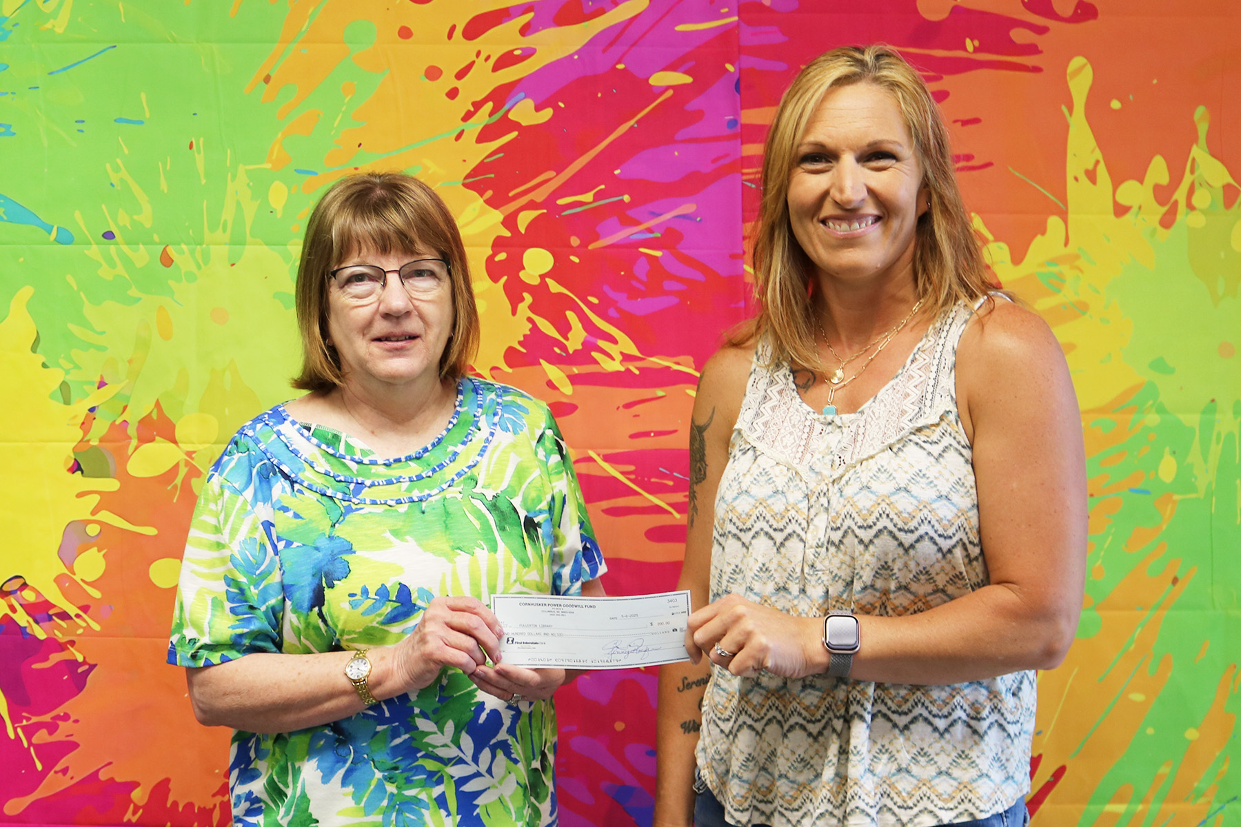 Cornhusker Public Power District Goodwill Fund Trustee Abie Czapla (right) presents $200 to the Fullerton Library for a bookshelf. Accepting the check is Library Assistant Leta Liesch (left). 