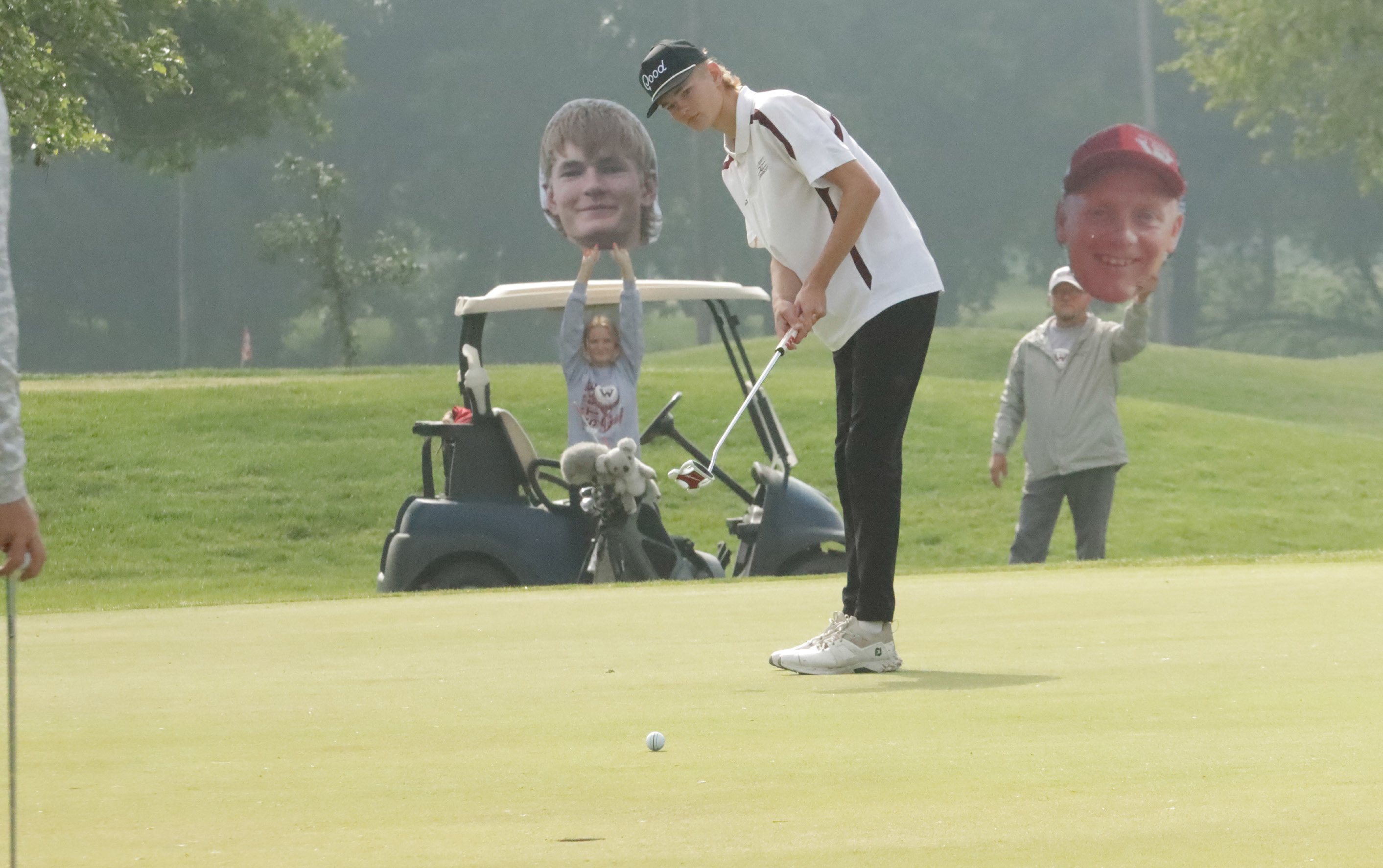 Cayden Scheffler watches his putt roll towards the cup with his fans cheering him on in the back ground. NCJ photos by Ken Kush