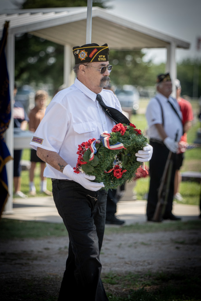 Tom Rice carries the wreath (above) to remember the fallen. He offers a salute (below).