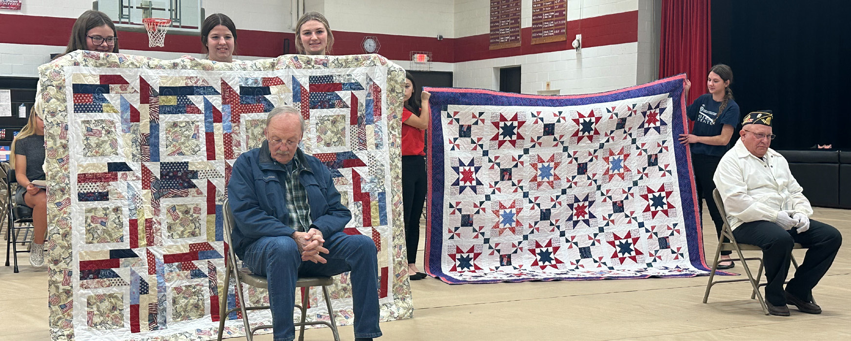 Chuck Bowman (seated left) and Monte Keith were presented with Quilts of Valor on Friday at Fullerton’s Veteran’s Day program. NCJ photo by Rick Holtz