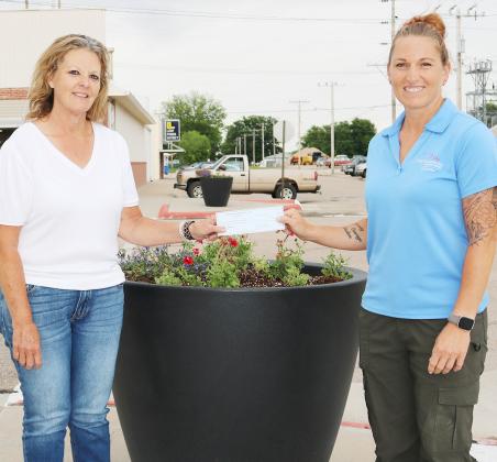 Cornhusker Public Power District Goodwill Fund Trustee Abie Czapla (right) presents $250 to Fullerton Area Chamber of Commerce for large flowerpots. Accepting the check is President Suzanne Schweitz (left).