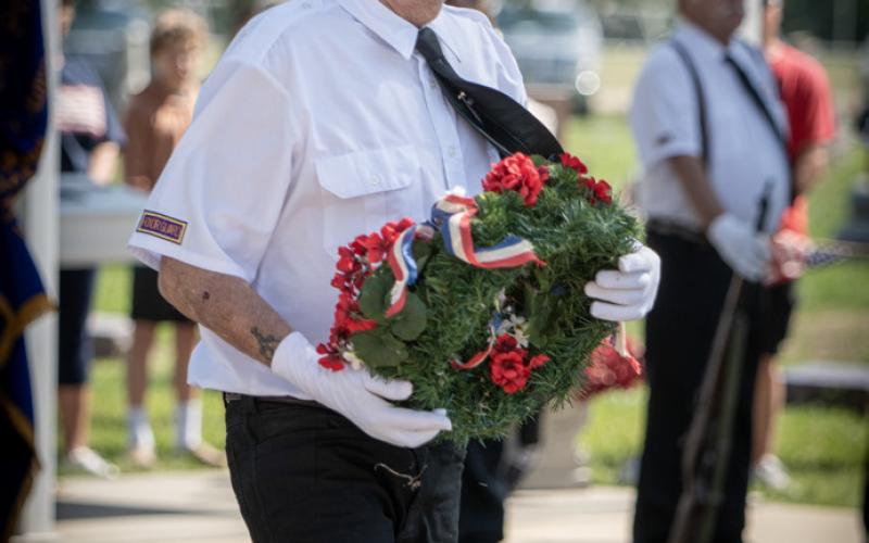 Tom Rice carries the wreath (above) to remember the fallen. He offers a salute (below).