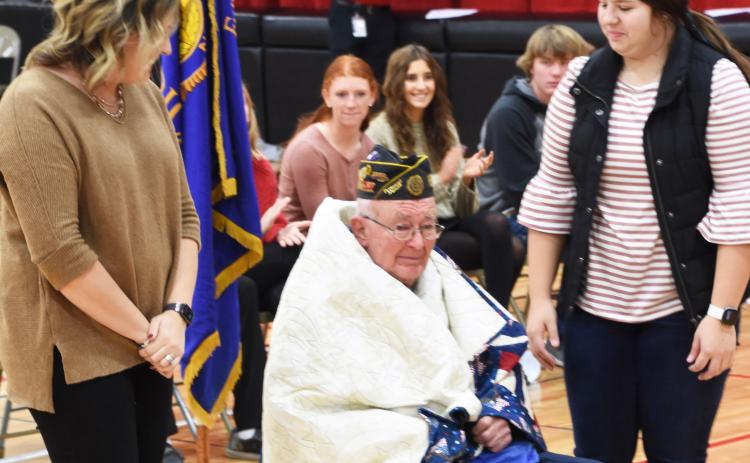 Army veteran Henry Bigge is shown wrapped in his Quilt of Valor. Placing the quilt around him were Beth Sonderup (left) and Melinda Pickrel, who together sewed the quilt.