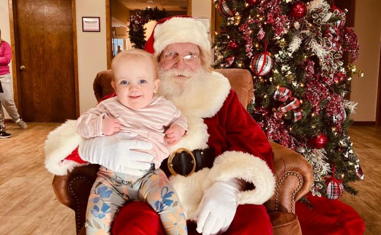 Evie Carroll, daughter of Sophie and Jonathon Caroll sits with Santa.