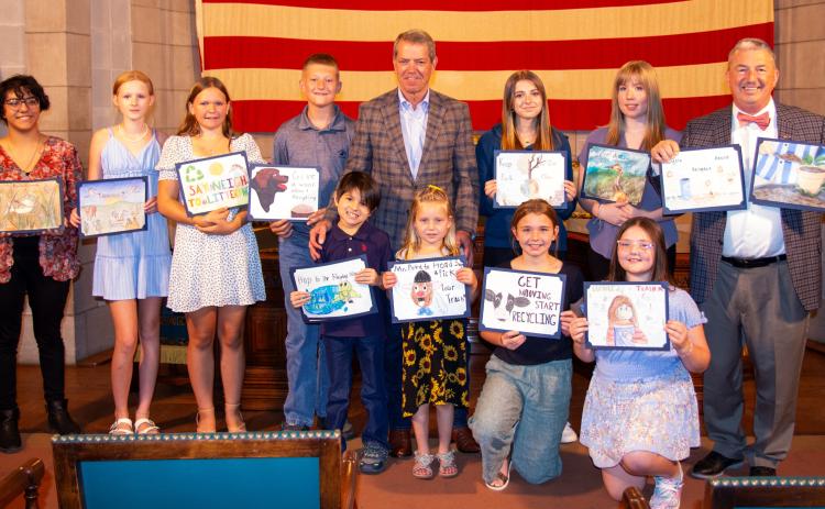 Gov. Jim Pillen and Nebraska Department of Environment and Energy Director Jim Macy honored 13 students whose artwork was chosen to be a part of the 2024 “Nebraska – Don’t Waste It!” calendar. Pictured are, from left: (front row) Gabriel Lobato, Lynae Shonka, Jacki Koch, and Daisy D’Agosto; and (back row) Nayeli Barraza; Elizabeth McNeely, Kassi Knael, Liam McColloch, Gov. Pillen, Ashtyn Quast, Eleanore Walters, and Director Macy. Not pictured are Kiersten Hans, Flora Dalton, and Chloe Shupp. Photo provided