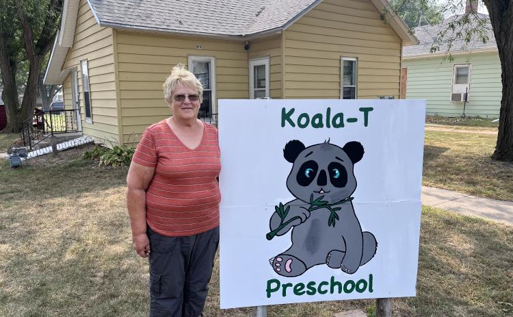 Mrs. Sims stands by of her Koala-T preschool sign. The preschool is in the background. NCJ photo by April Carr