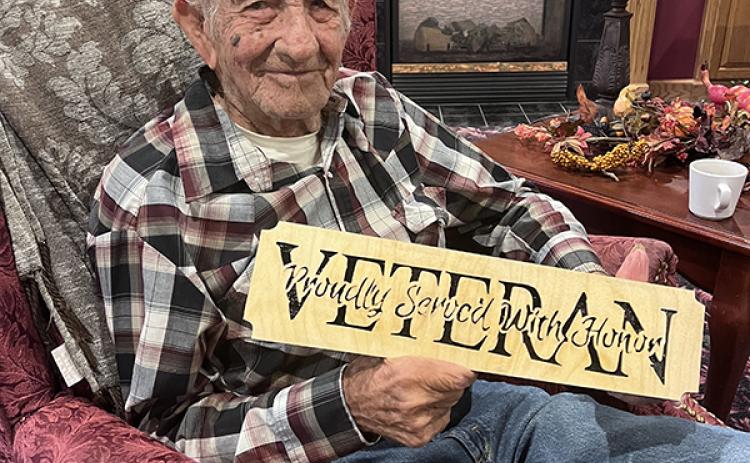 Larry Phillips is pictured with one of the signs he has made. NCJ photo by April Carr