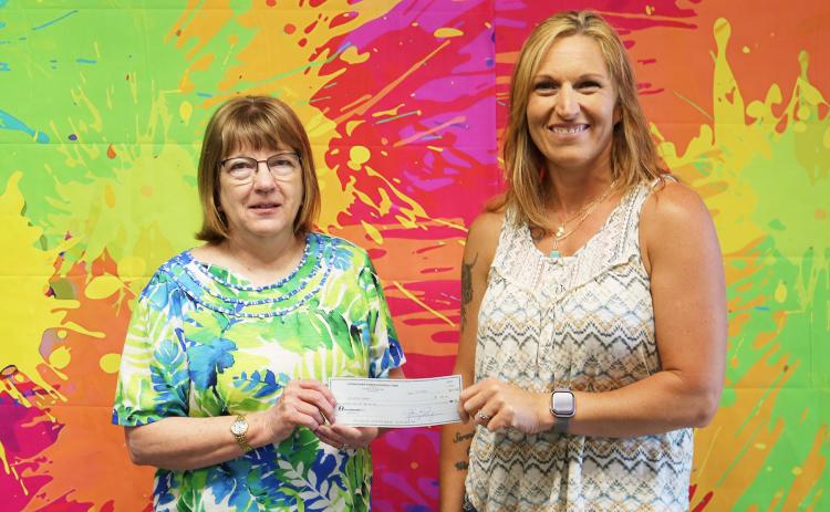 Cornhusker Public Power District Goodwill Fund Trustee Abie Czapla (right) presents $200 to the Fullerton Library for a bookshelf. Accepting the check is Library Assistant Leta Liesch (left).