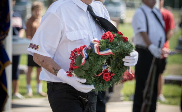 Tom Rice carries the wreath (above) to remember the fallen. He offers a salute (below).