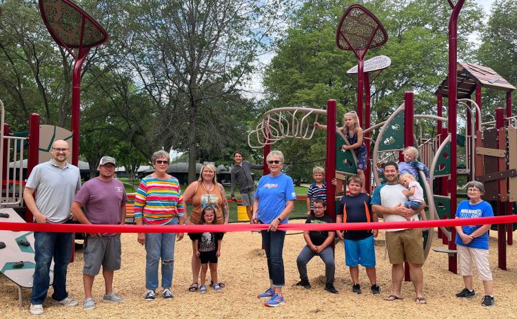 The city officially opened its newest playground last week. Those attending the ribbon cutting include: Allen Chlopek (left), KC Rieken, Wylene Novicki, Tessa Nelson, Jennifer Carr, Jackson Carr, Jan Hellbusch, Archie Nelson, Hudson Carr, Americus Nelson, Dusin Schock, Everly Schock, Freya Schock and Jane Swartz. NCJ photo by April Carr