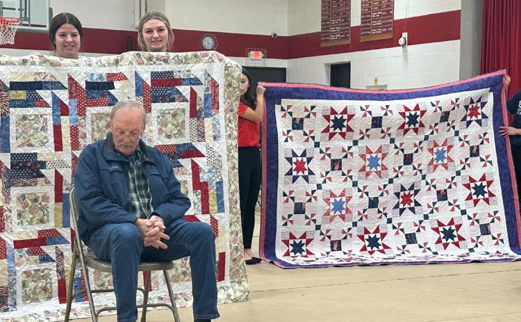 Chuck Bowman (seated left) and Monte Keith were presented with Quilts of Valor on Friday at Fullerton’s Veteran’s Day program. NCJ photo by Rick Holtz